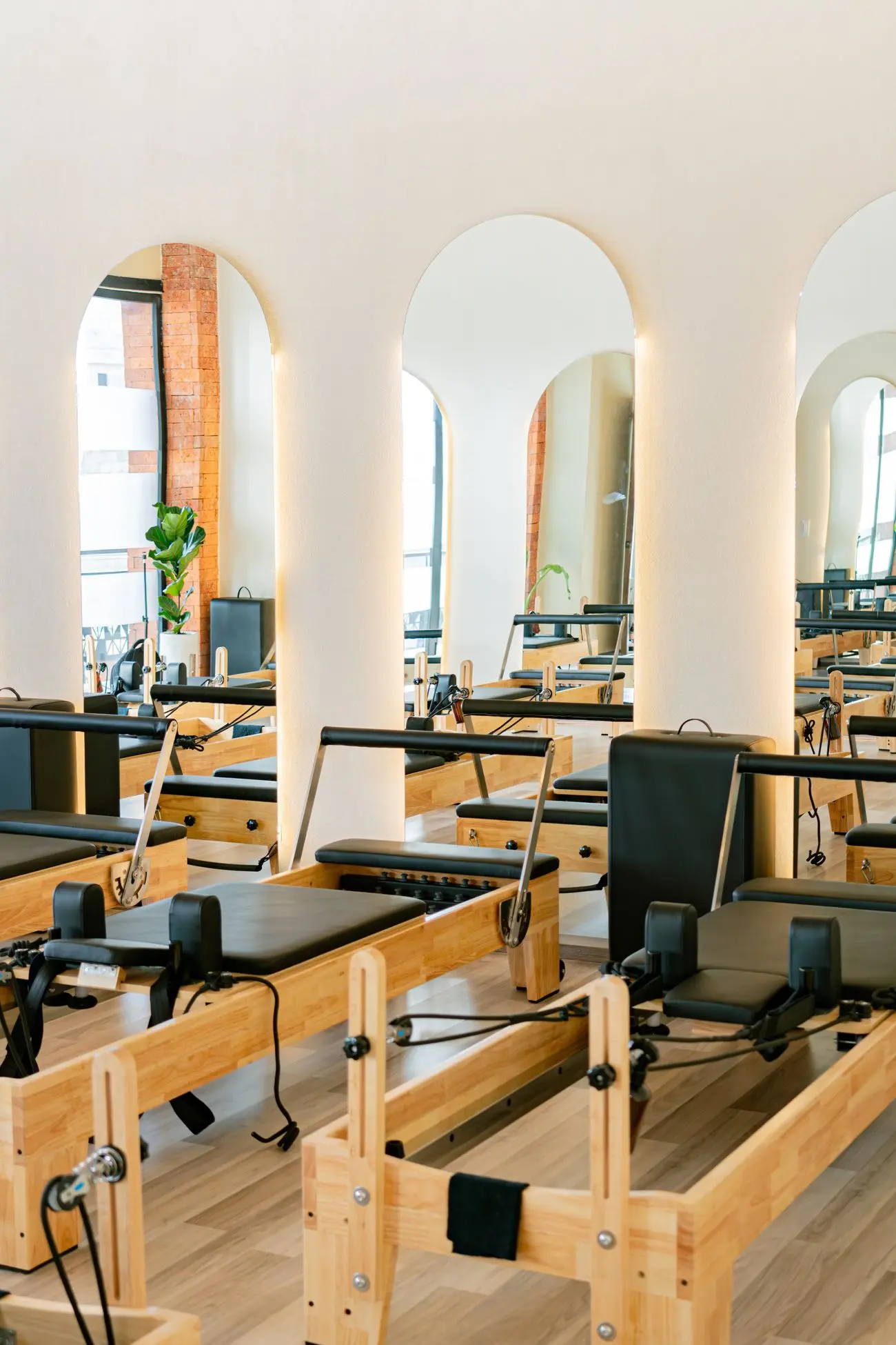 Pilates reformers lined up beneath tall arched mirrors