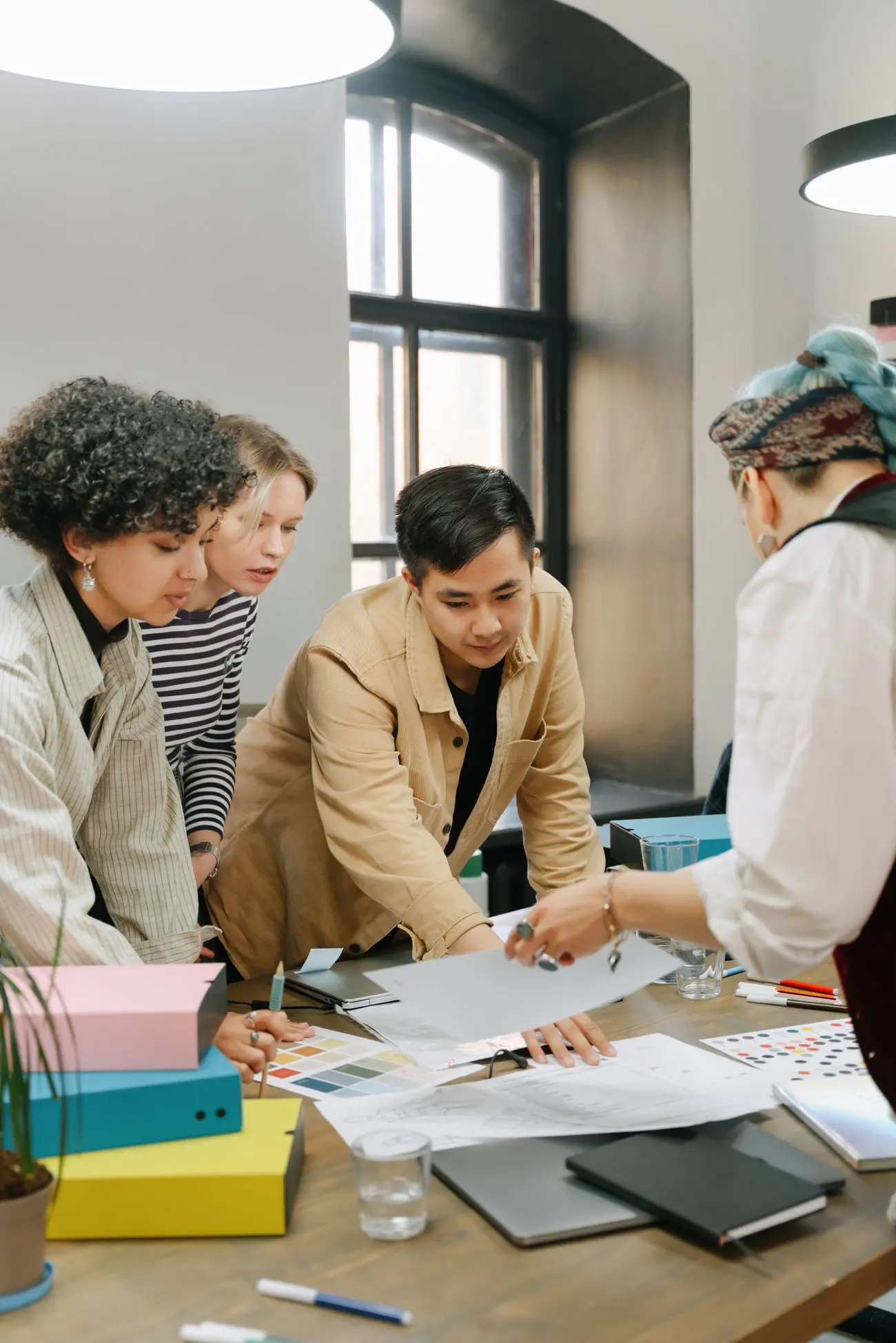 A team leaning over plans and colour samples on a table