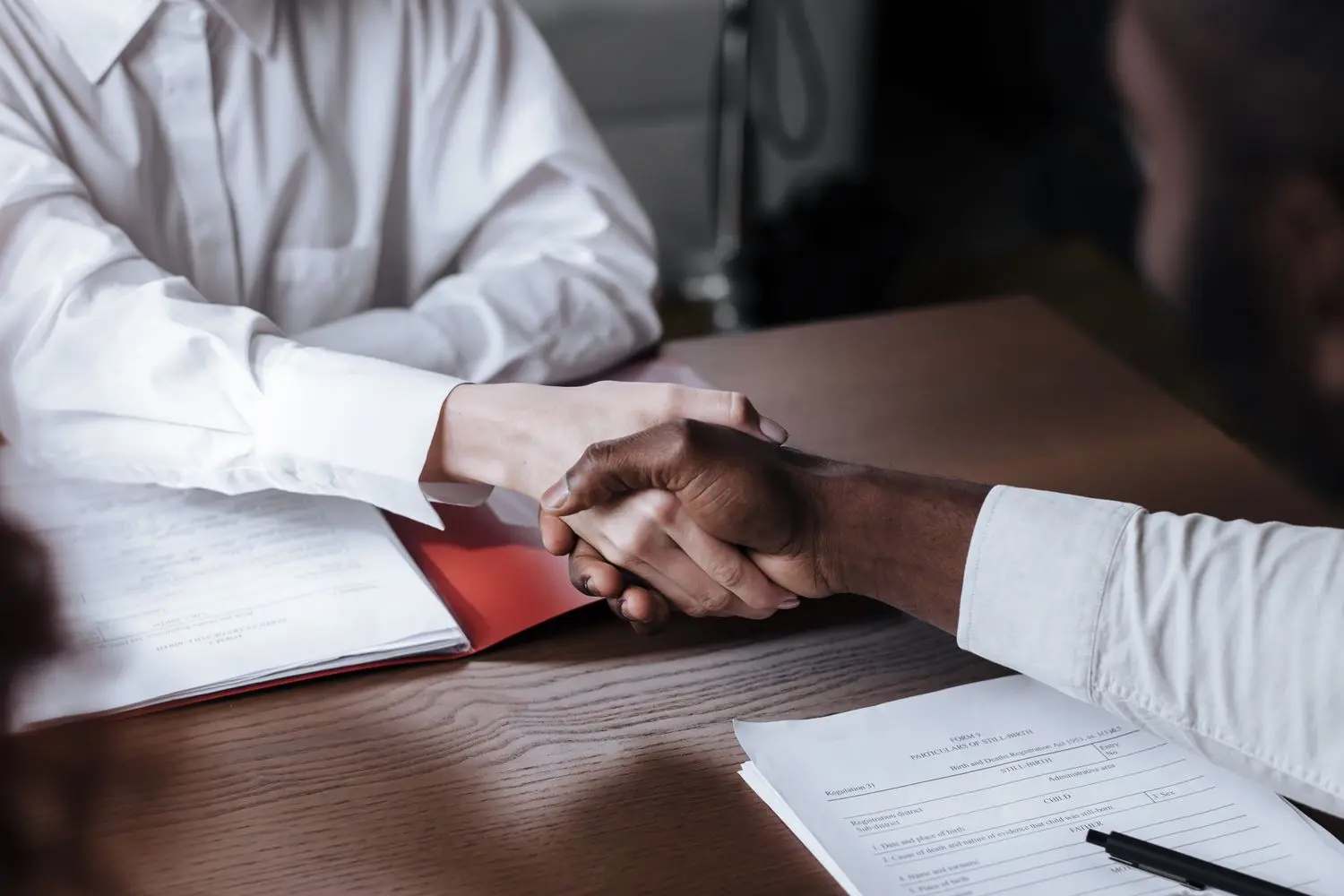 Two people shaking hands across a table
