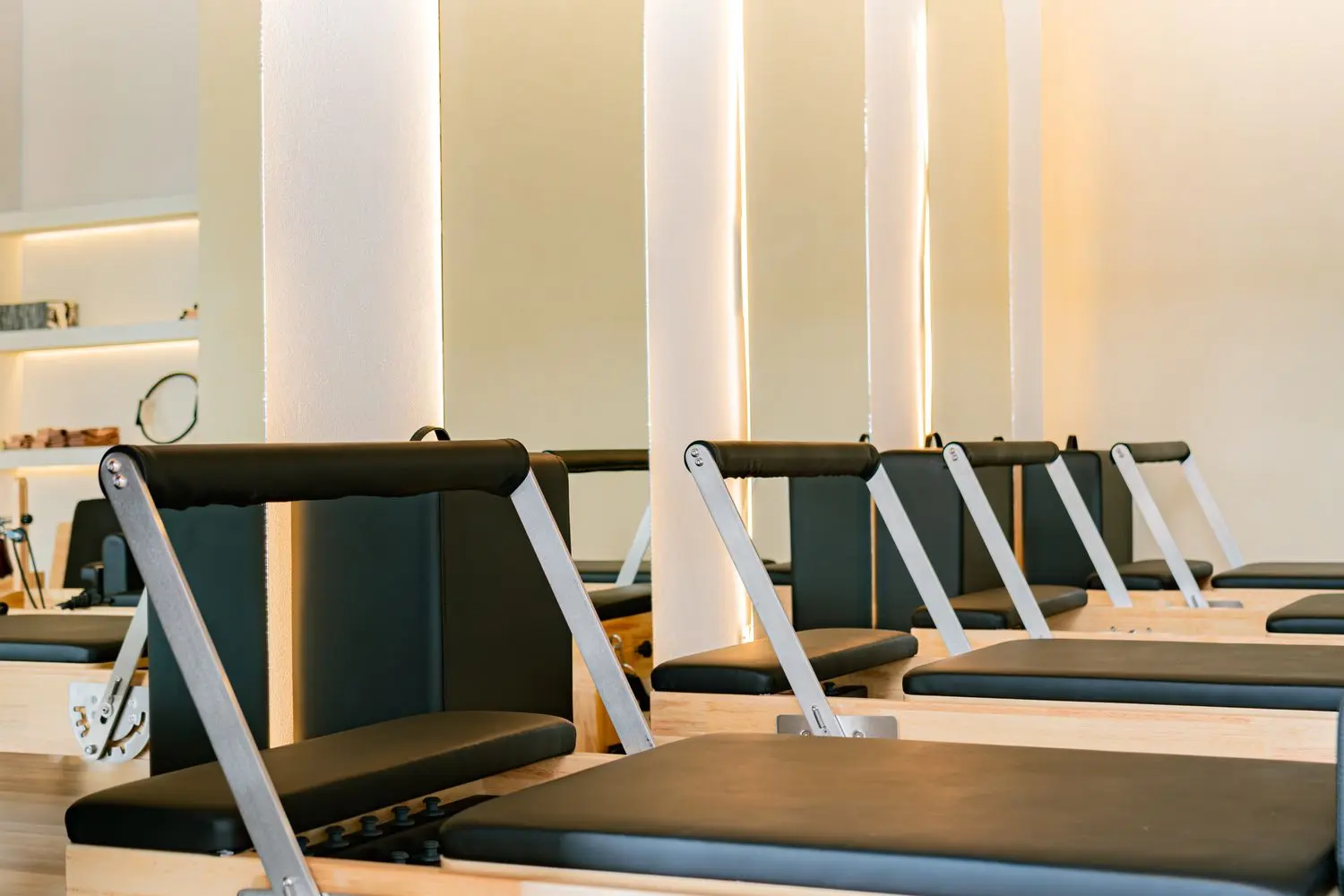 A row of pilates reformers in a softly lit studio